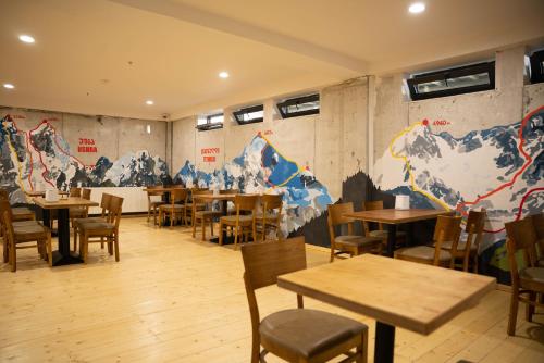 a restaurant with tables and chairs and a wall with mountains at Lahili Boutique Hotel in Mestia