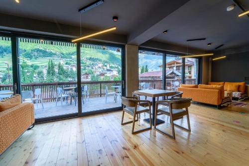 ein Wohnzimmer mit einem Tisch und Stühlen sowie einem Balkon in der Unterkunft Hotel Lahili in Mestia