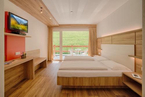 a bedroom with two beds and a television on a wall at Oberjahrl in San Giovanni in Val Aurina