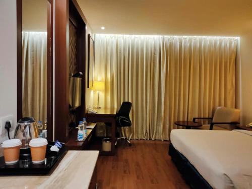 BhiwadiにあるCountry Inn & Suites by Radisson, Bhiwadiのベッドとデスクが備わるホテルルームです。