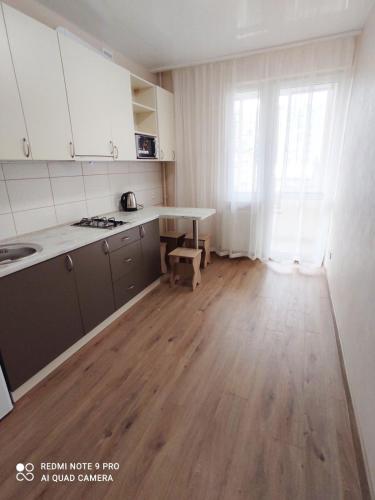 cocina con armarios blancos y suelo de madera en Елітна квартира в новобудові, en Leópolis