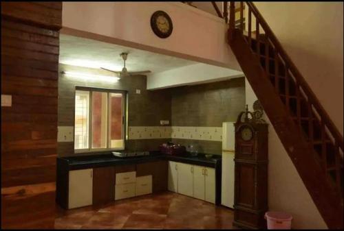 una cocina con una escalera y un reloj en la pared en Shattarka Villa en Alibaug