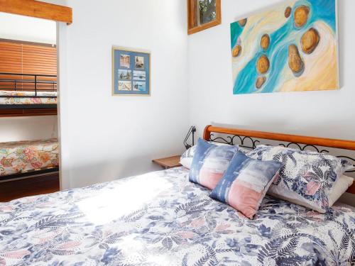 a bedroom with a bed with pillows and a painting at Bennett's Beach Cottage in Hawks Nest