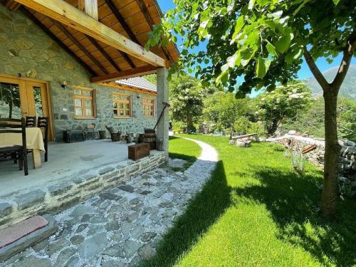 a stone house with a patio and a yard at Bujtina Peshtan Guesthouse&Camping in Tepelenë