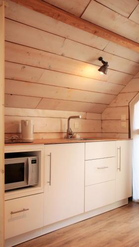 une cuisine avec des armoires blanches et un micro-ondes dans l'établissement La Vinotière Chambres Appartements Spa, au Conquet