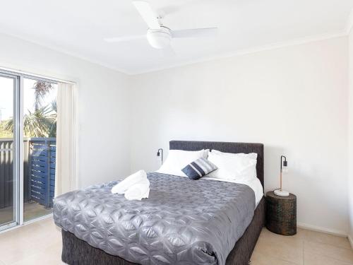 a white bedroom with a large bed with white pillows at Seachange Apartment 2 in Hawks Nest