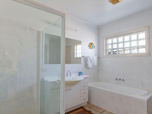 a white bathroom with a sink and a shower at Seachange Apartment 2 in Hawks Nest