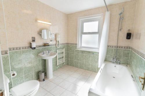 a bathroom with a tub and a toilet and a sink at The Pier Hotel in Eastbourne