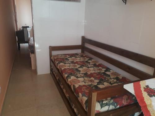 a bedroom with a bed with a floral quilt on it at Praia da Maria in Ubatuba