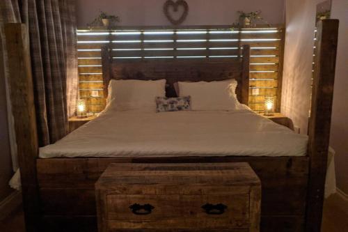 a large bed with a wooden headboard and two night stands at Tarff Church Sunday school. With hot tub and sauna in Twynholm