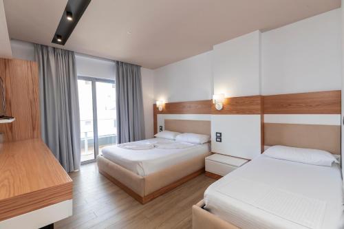 a hotel room with two beds and a window at Ventus Hotel in Ksamil