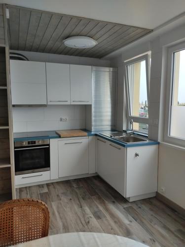 une cuisine avec des armoires blanches et des comptoirs bleus dans l'établissement Au repos des baigneurs, appartement rez-de-chaussée, WIFI, au Tréport