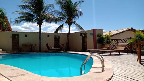 a swimming pool with palm trees in a yard at Pousada Nova Oasis do Rei in Canoa Quebrada