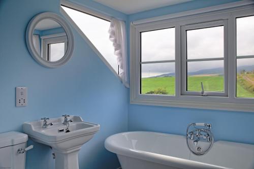 a bathroom with a sink and a tub and a mirror at Arthur's Cottage in Dumfries