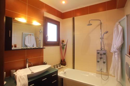 y baño con bañera, lavamanos y ducha. en Villa Adelais, en Tsoukaladhes