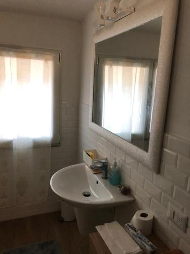 La salle de bains blanche est pourvue d'un lavabo et d'un miroir. dans l'établissement Ducale Estense Suite Apartment, à Modène