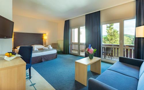 Habitación de hotel con cama y sofá en Hotel Rhön Residence en Dipperz