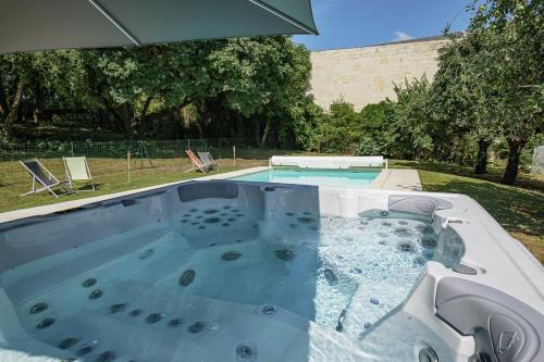 un grand bain à remous dans un jardin avec une piscine dans l'établissement Château des Orchidées en Val de Loire, à Saumur
