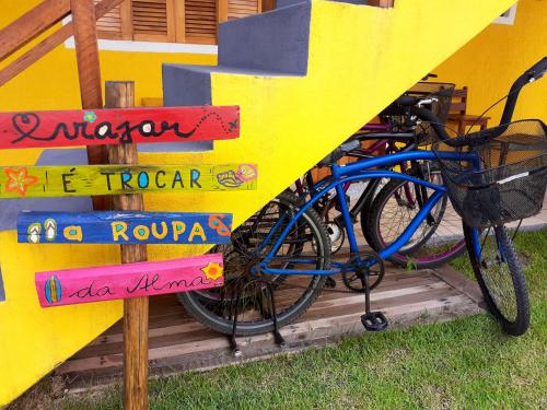 ein blaues Fahrrad, das neben einer gelben Wand mit Schildern parkt in der Unterkunft A Ver o Mar Beach House in Caraguatatuba