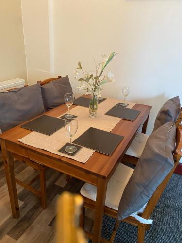 uma mesa de madeira com dois copos de vinho e um sofá em Gables Seaview 4 school Str Largs top floor em Largs