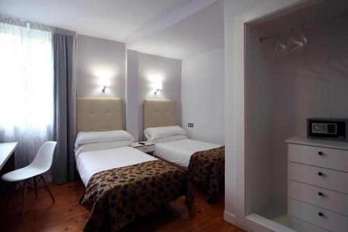 a room with two beds and a desk and a dresser at Casual Gurea in Bilbao