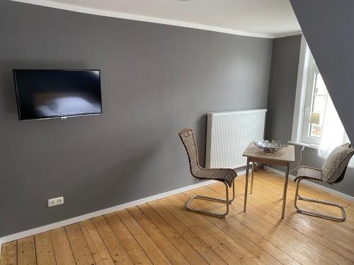 a room with two chairs and a table and a tv on the wall at Altstadt Fereienwohnung Hameln in Hameln