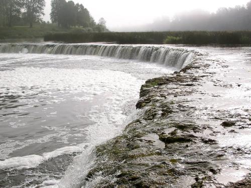 a waterfall in front of a river at Hercoga Jekaba Apartaments in Kuldīga