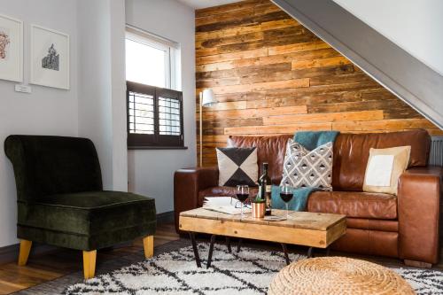 a living room with a leather couch and a chair at By the Way in Great Malvern