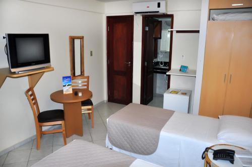 a bedroom with a bed and a television and a table at Rede Andrade Bello Mare in Natal