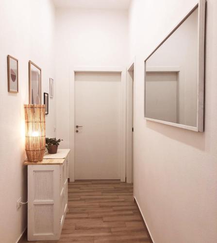 a hallway with a white door and a mirror at SUITE BLANC APARTMENTS - Monolocali indipendenti con cucina e bagno privato - Check-in e check-out con codice in autonomia h24 - Terrazza in comune NECESSARIO AVERE WATHSAPP O APP DI MESSAGGISTICA ISTANTANEA PER FOTO E VIDEO in Guspini