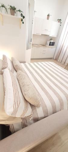 a bed with pillows on it in a room at SUITE BLANC APARTMENTS - Monolocali indipendenti con cucina e bagno privato - Check-in e check-out con codice in autonomia h24 - Terrazza in comune NECESSARIO AVERE WATHSAPP O APP DI MESSAGGISTICA ISTANTANEA PER FOTO E VIDEO in Guspini