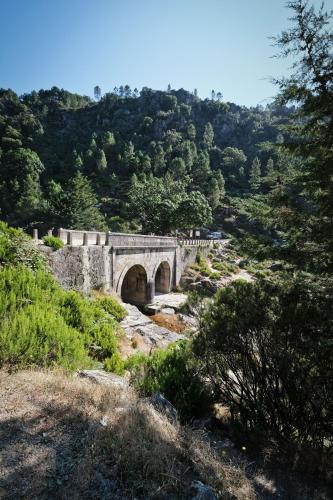 a stone bridge over a river in a mountain at Casa do Lago - Geres in Geres