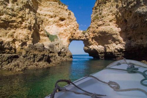 een boot in het water voor een rotsgrot bij Casa do João in Barão de São João