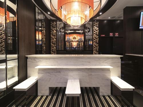 a lobby with a marble bar with benches and a chandelier at APA Hotel Shin-Osaka-Ekiminami in Osaka