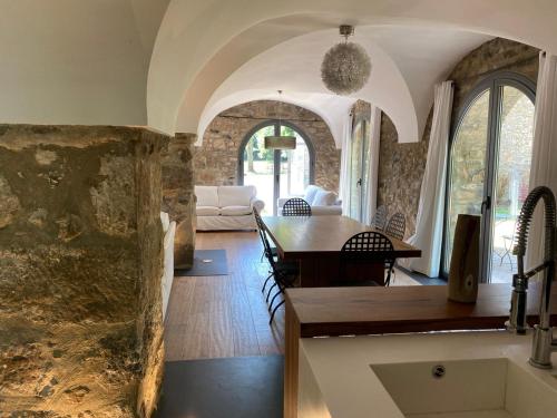comedor y sala de estar con pared de piedra en Casa Rural el Serrat de Baix, en Sant Joan les Fonts