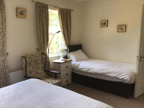 a bedroom with two beds and a chair and a window at Orchard Grove in Bagenalstown