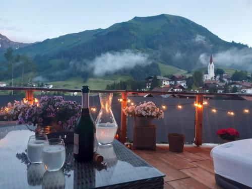 uma mesa com garrafas de vinho e copos numa varanda em Hideaway Zugspitz Berwang em Berwang