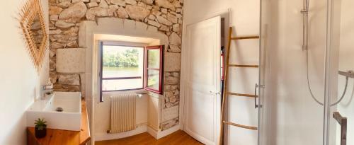 ein Badezimmer mit einer Steinmauer und einem Fenster in der Unterkunft Le bistrot de l'écluse in La Roussiere