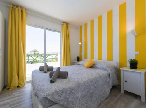 a bedroom with a bed with yellow and white stripes at Sweet apartment maspalomas in Maspalomas