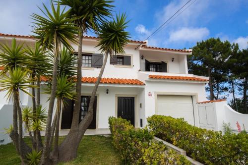 een wit huis met palmbomen ervoor bij West coast dream Nazare in Nazaré