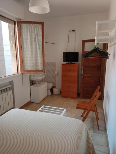 a bedroom with a bed and a television and a chair at Pensión Los Pinos Gijón in Gijón