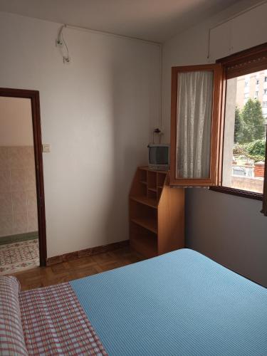 a bedroom with a blue bed and a window at Pensión Los Pinos Gijón in Gijón