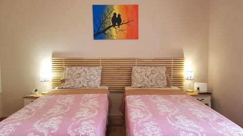 two beds in a small room with pink sheets and a painting at LIBERTY ΙΩΑΝΝΙΝΑ in Ioannina
