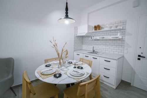 a white kitchen with a table and some chairs at Luxury Central Studio in Xanthi
