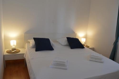 a large white bed with two pillows and two lamps at Holiday home Petra in Vinišće
