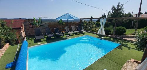 duży niebieski basen z krzesłami i parasolem w obiekcie Amazing Milk and Honey cottage with hill views w mieście Novi Marof