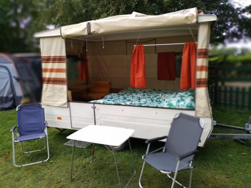 a camper with chairs and a table in the grass at Retro Vouwwagen in Tynaarlo