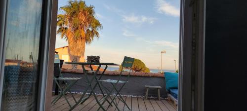 d'un balcon avec une table, des chaises et un palmier. dans l'établissement Maison de vacances à l'Ayguade classée 3 étoiles, climatisée,3mn à pied plage et restos ,5mn aéroport, 10mn gare, à Hyères