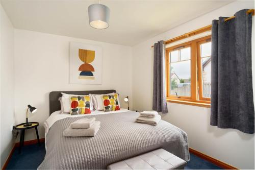 1 dormitorio con 1 cama con toallas en The Nook Holiday Cottage, en Aviemore