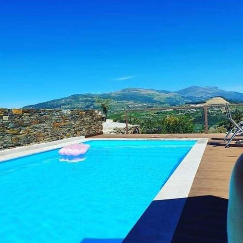 a large blue swimming pool with a mountain in the background at Quinta do Pombal - Douro - Camila's in Lamego